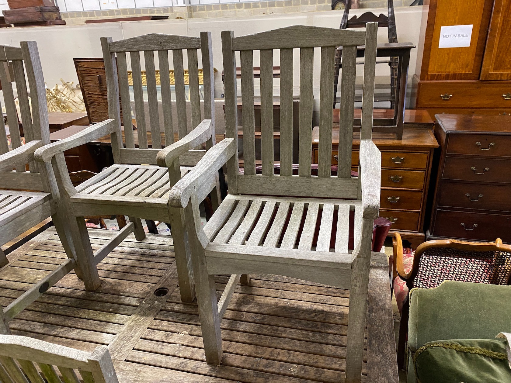 A rectangular weathered teak garden table, length 183cm, depth 92cm, height 73cm and seven Lister teak garden elbow chairs